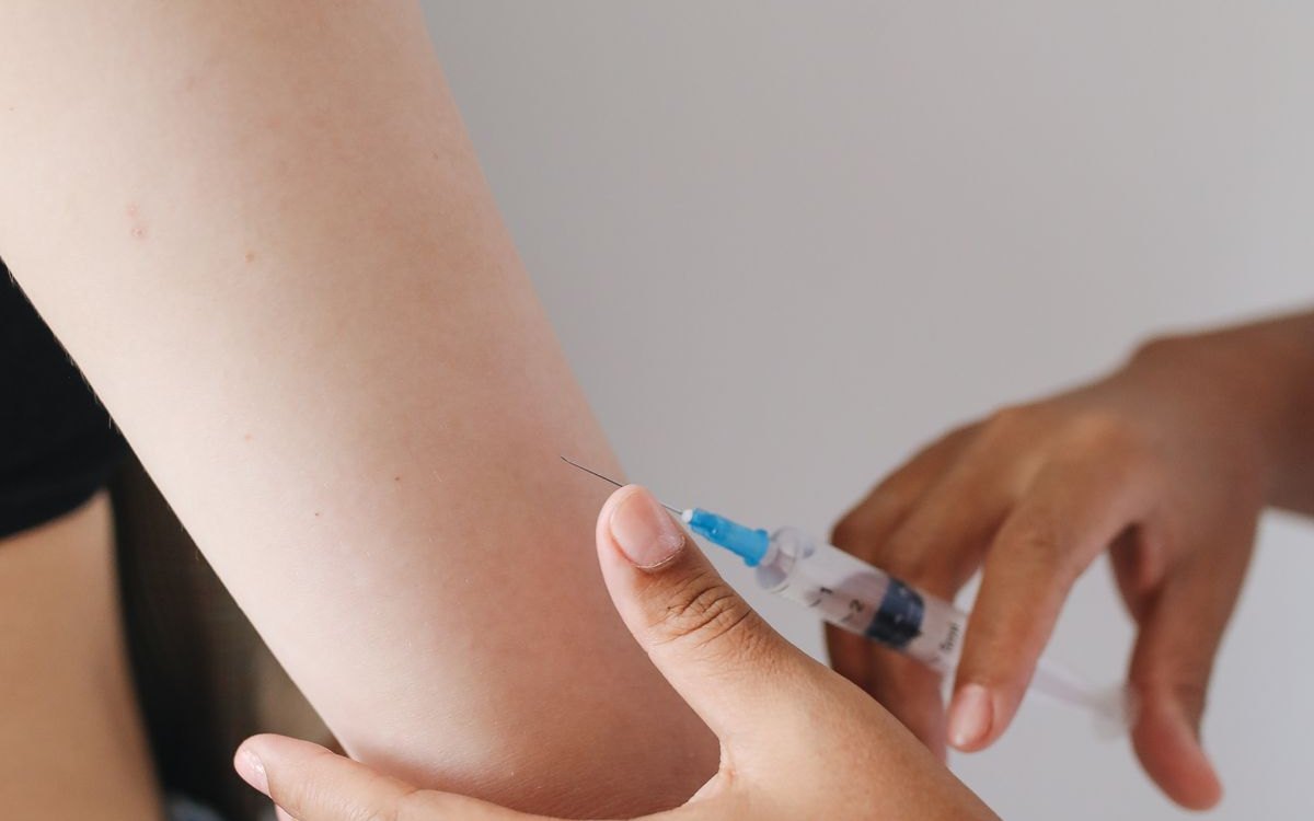 A clinician giving a subcutaneous injection into a patient's upper arm