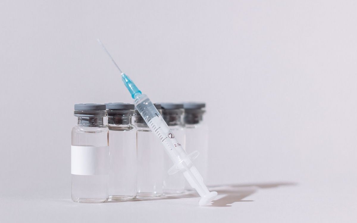 A prepared syringe resting against a row of clear medication vials